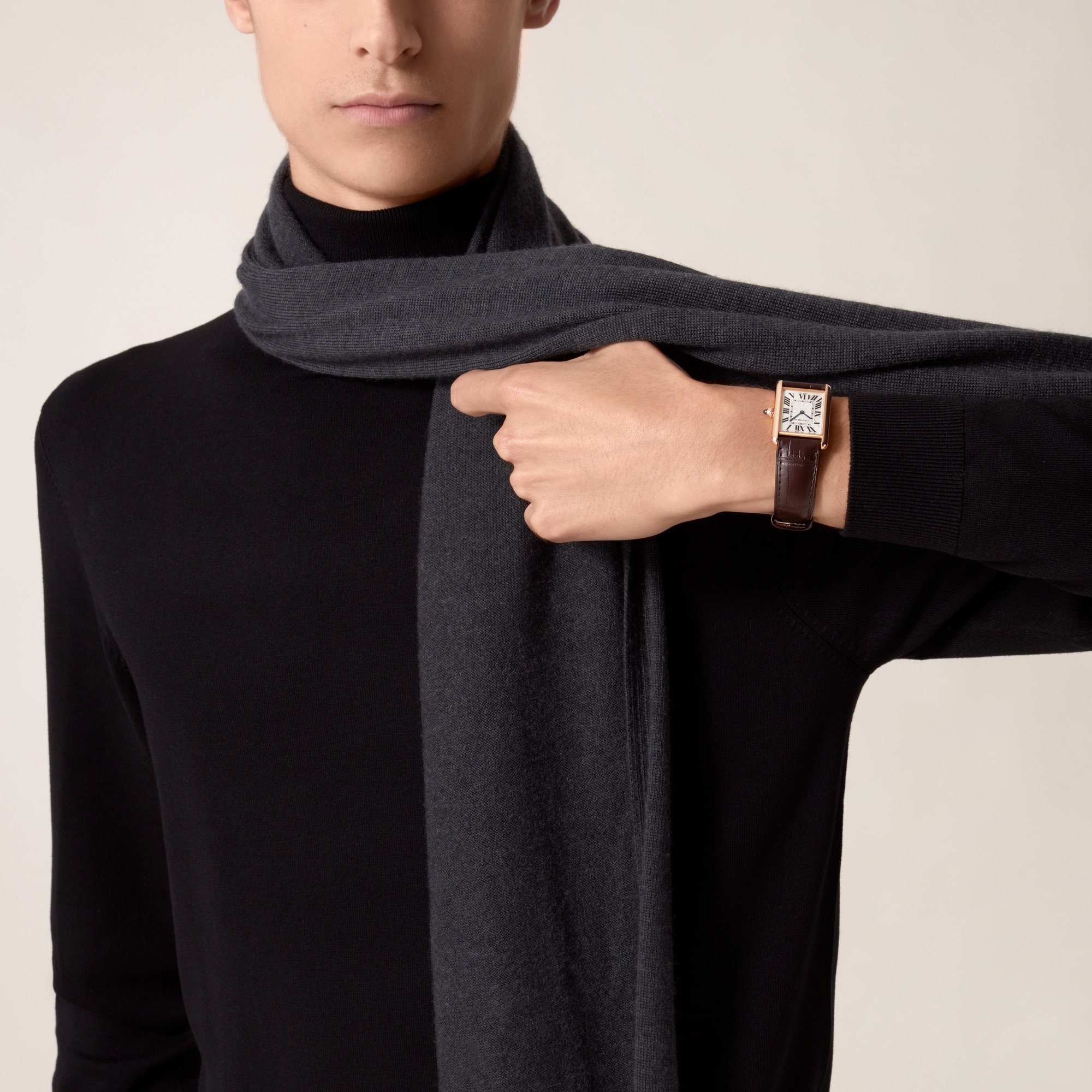 Fashionable on-wrist shot of a Dupe Tank Louis Cartier large model rose gold color watch with dark brown leather strap, worn by a male model with dark attire.
