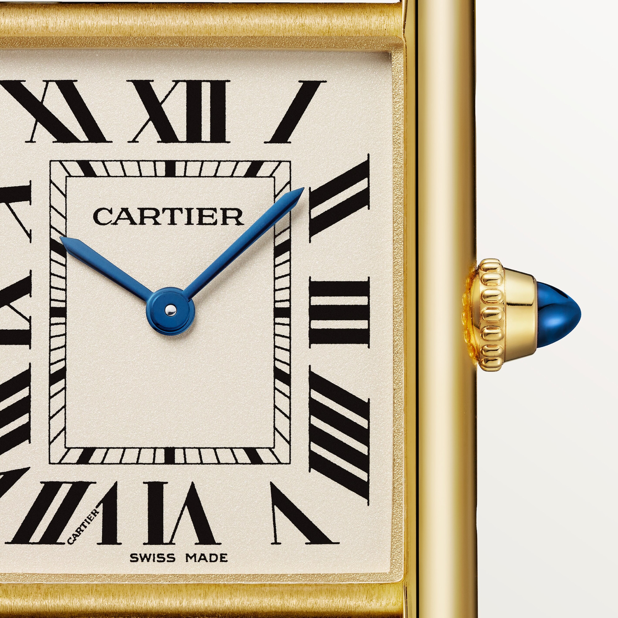 Macro shot: Dial of Dupe Tank Louis Cartier large model watch, yellow gold colors case, with Roman numerals, blue hands, and blue spinel crown.