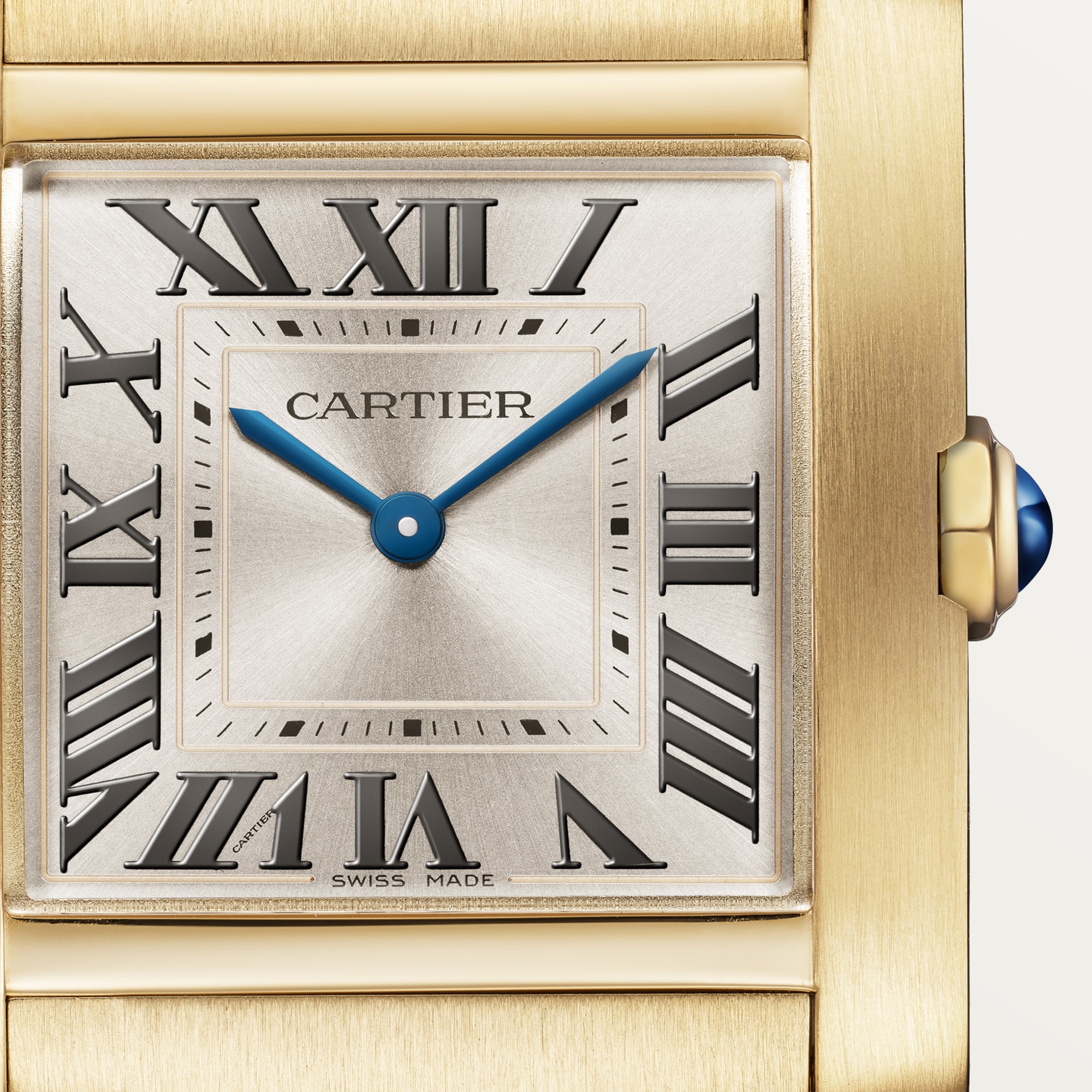 Macro shot: Dial of Dupe Tank Française medium model watch, yellow gold colors case, with Roman numerals, blue hands, and blue spinel crown.