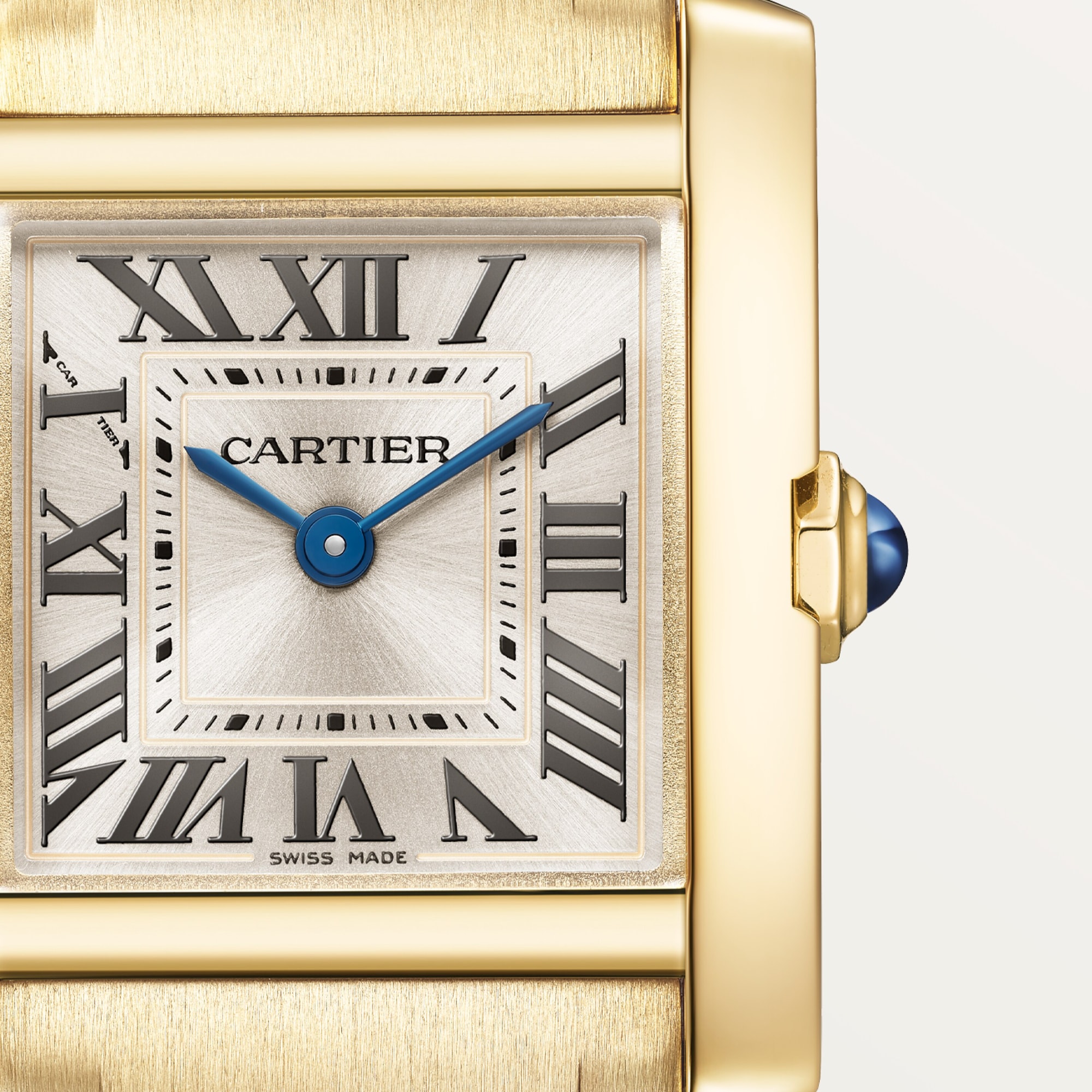 Macro shot: Dial of Dupe Tank Française small model watch, yellow gold colors case, with Roman numerals, blue hands, and blue spinel crown