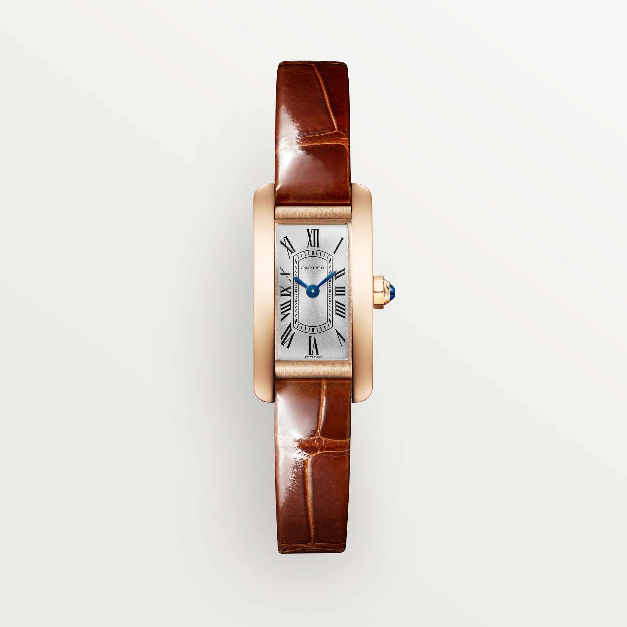 Front view: Dupe Tank Américaine mini model watch with a rose gold colors curved case, silver-white dial, and brown leather strap.