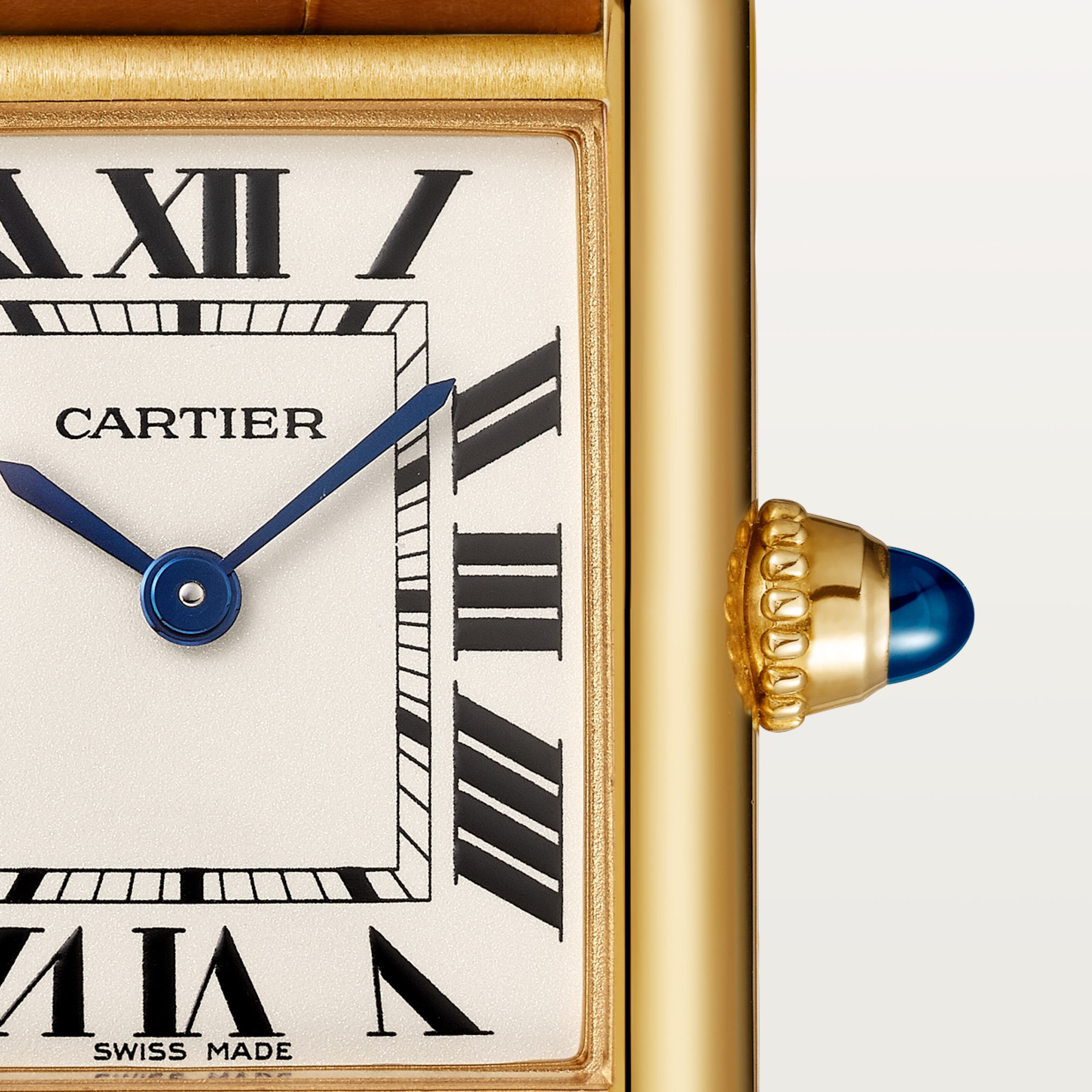 Macro shot: Dial of Dupe Tank Louis Cartier small model watch, yellow gold colors case, with Roman numerals, blue hands, and blue spinel crown.