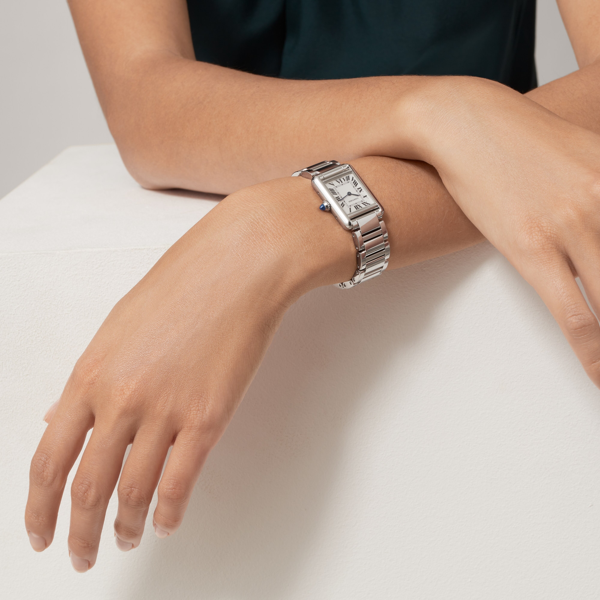Woman's wrist wearing a small steel Tank Must dupe Cartier watch, showcasing its elegant fit.