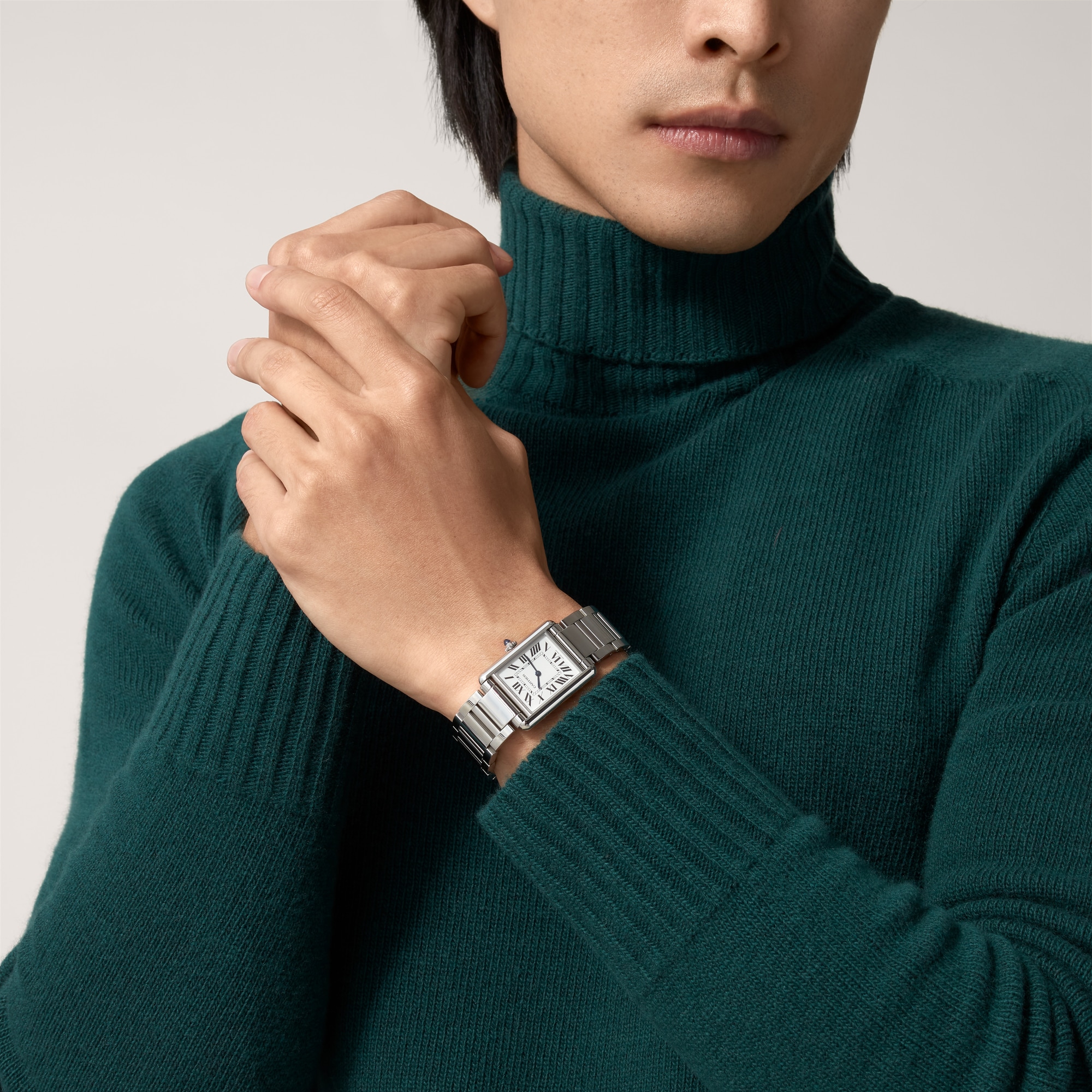 Man wearing a large steel Tank Must dupe Cartier watch, highlighting its size and classic style.