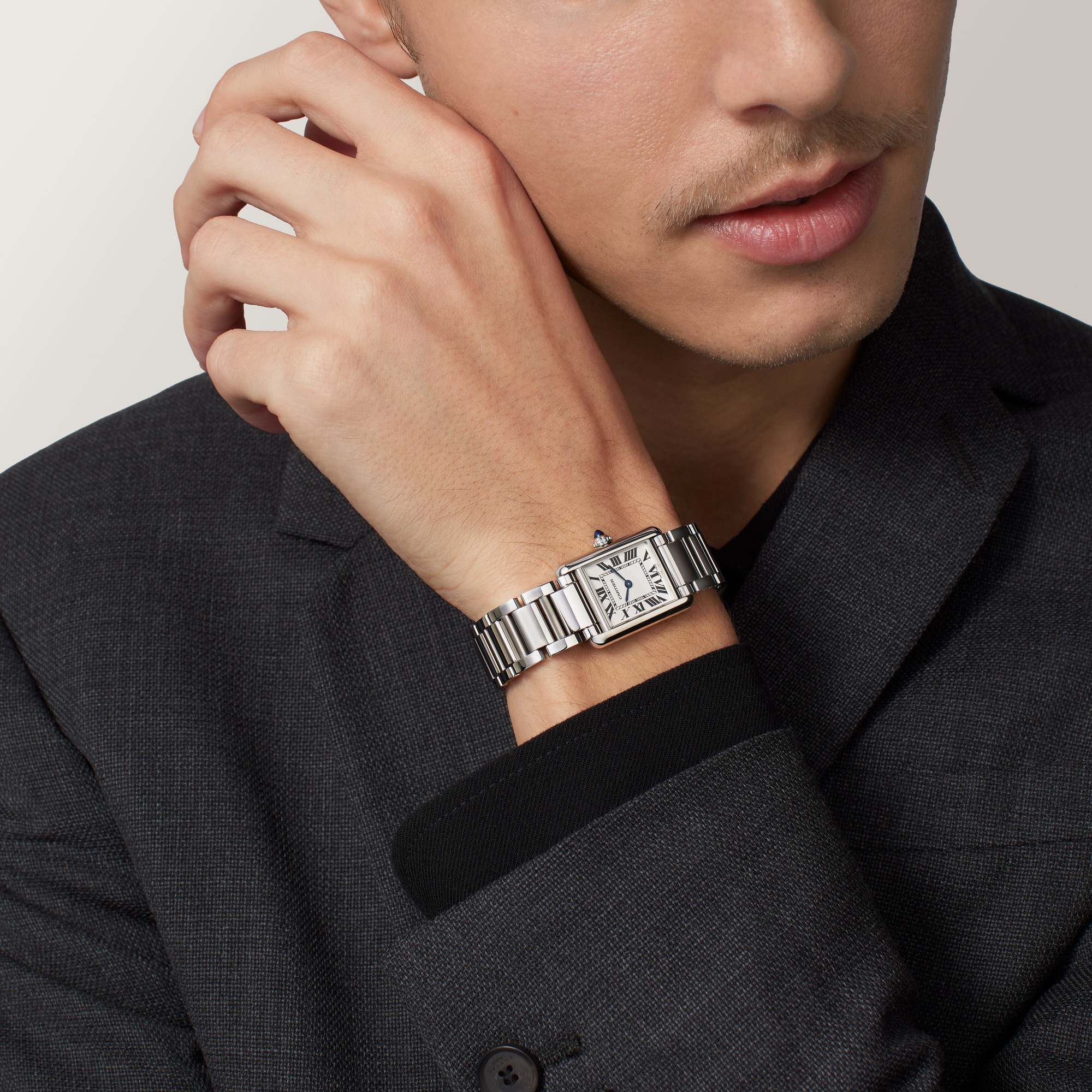 Man's wrist wearing the small Tank Must Solarbeat™ dupe Cartier watch with a steel case and matching bracelet.