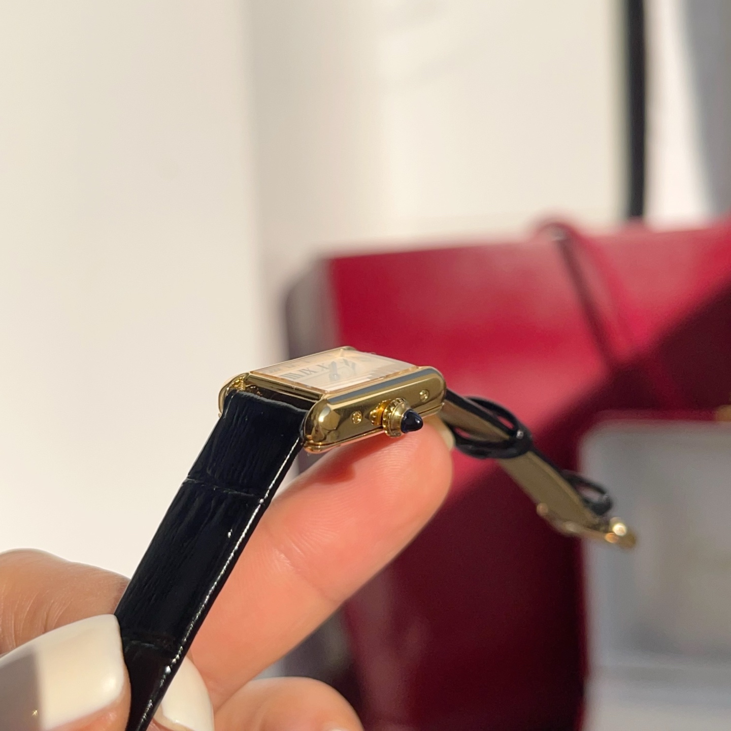 AF Super Clone Cartier Tank Louis replica watch held in hand, focusing on the gold case and cream dial.