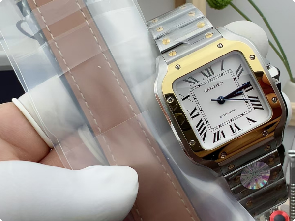 Overhead shot of the Santos de Cartier two-tone watch from BVF Factory, displayed alongside the complimentary leather strap, illustrating the QuickSwitch strap system.