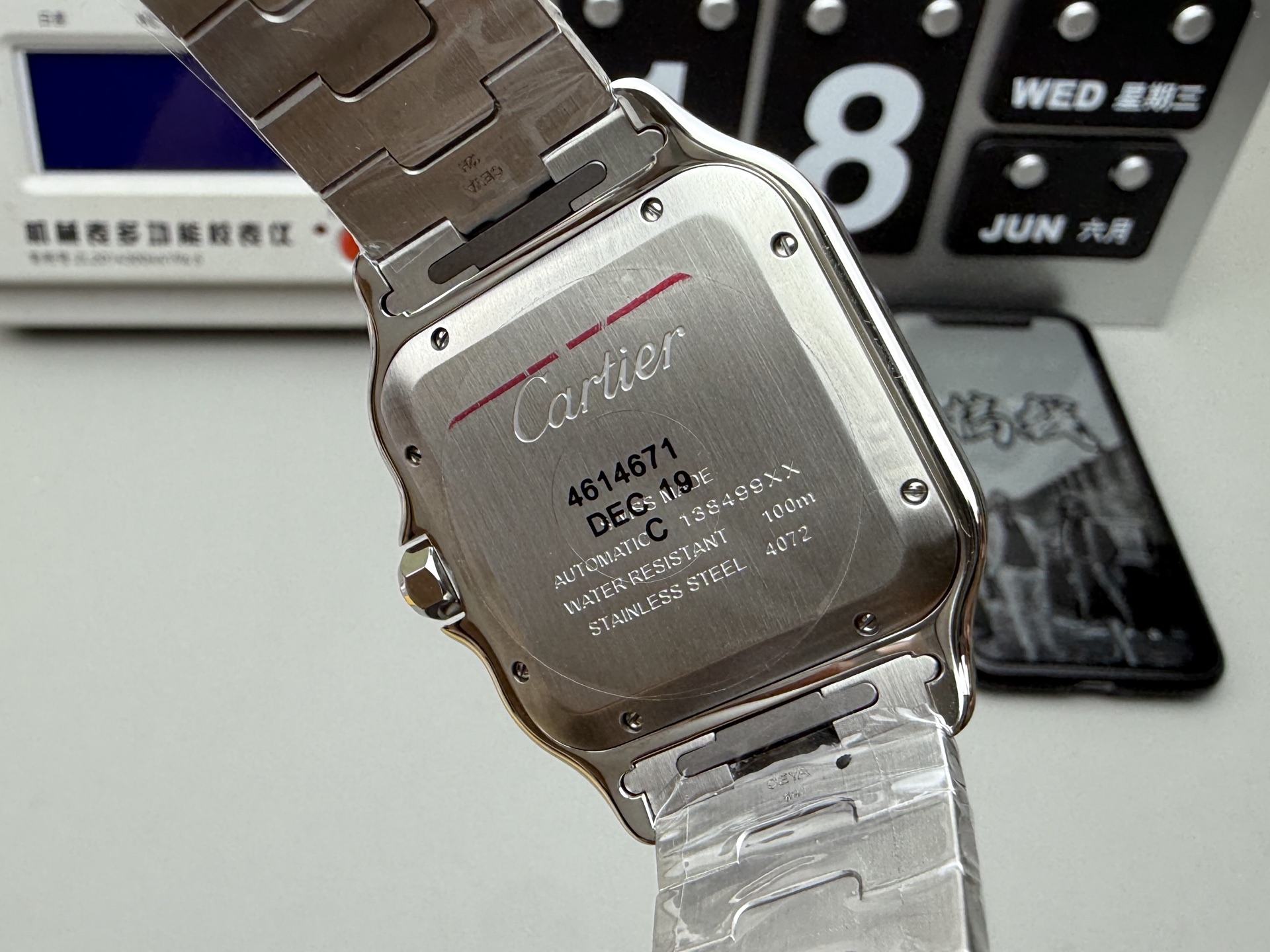 Detailed close-up of the caseback of the BVF Super Clone Cartier Santos replica watch, showcasing engravings and model information, held by a gloved hand.