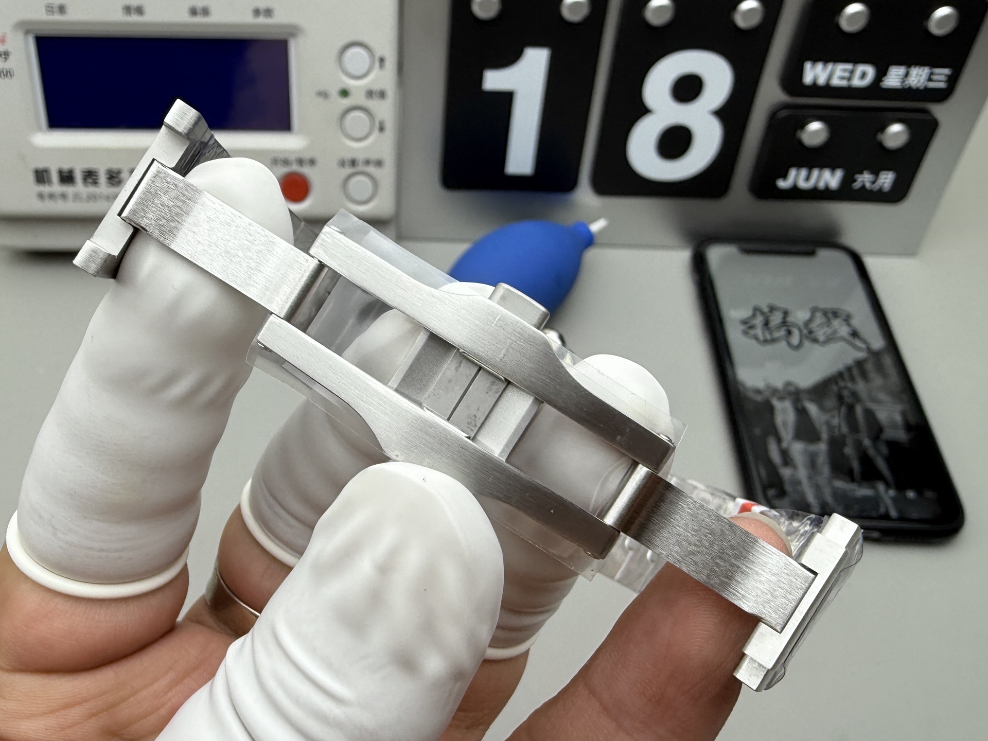 Close-up of the steel folding clasp of the BVF Super Clone Cartier Santos replica watch, held by a gloved hand, showing its internal mechanism.